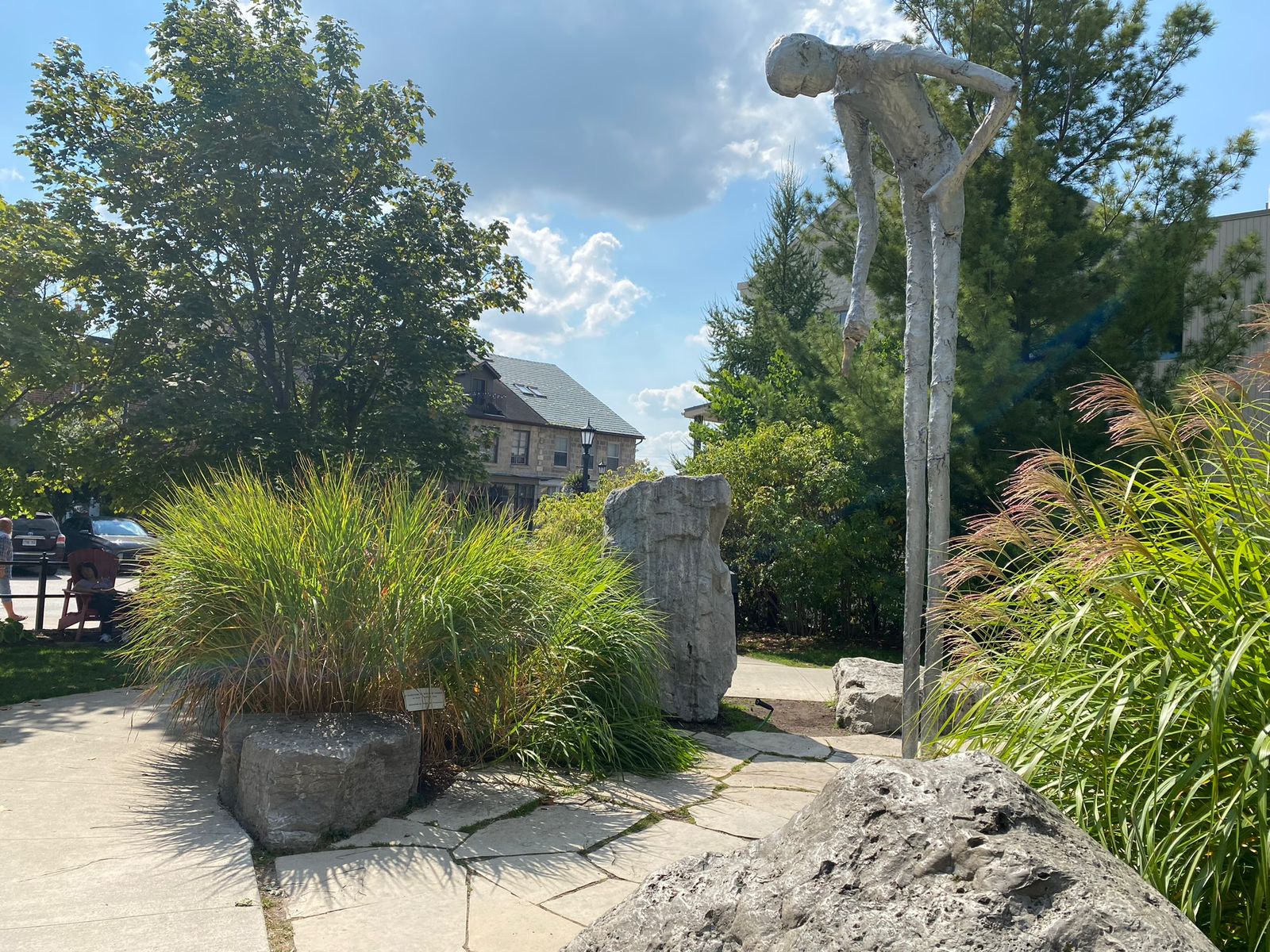 A garden path beside a weathered standing stone among green planting