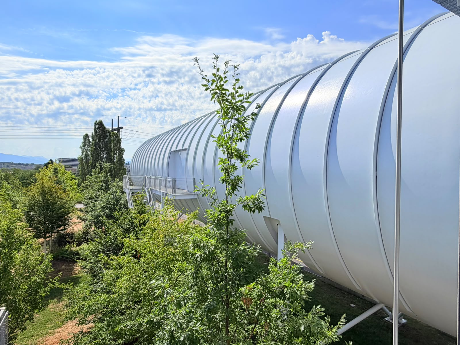 A long ribbed cylindrical walkway through a green park