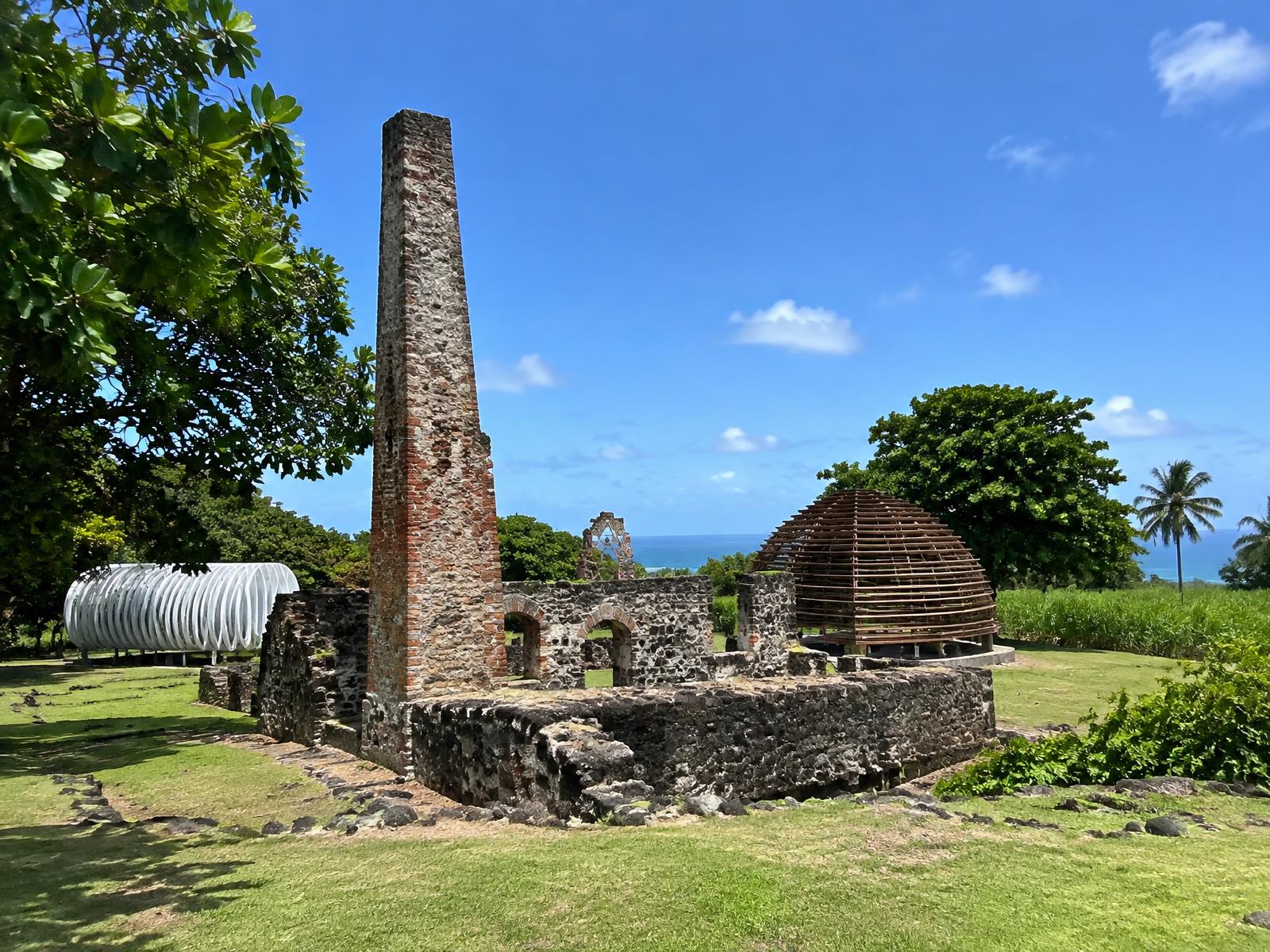 Ruins of a Caribbean sugar estate with a stone chimney beside cane fields